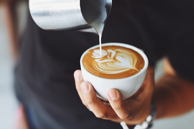 person doing latte art in a coffee cup